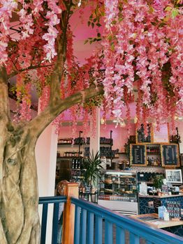 A cozy cafe adorned with stunning artificial pink wisteria flowers and rustic interior design.