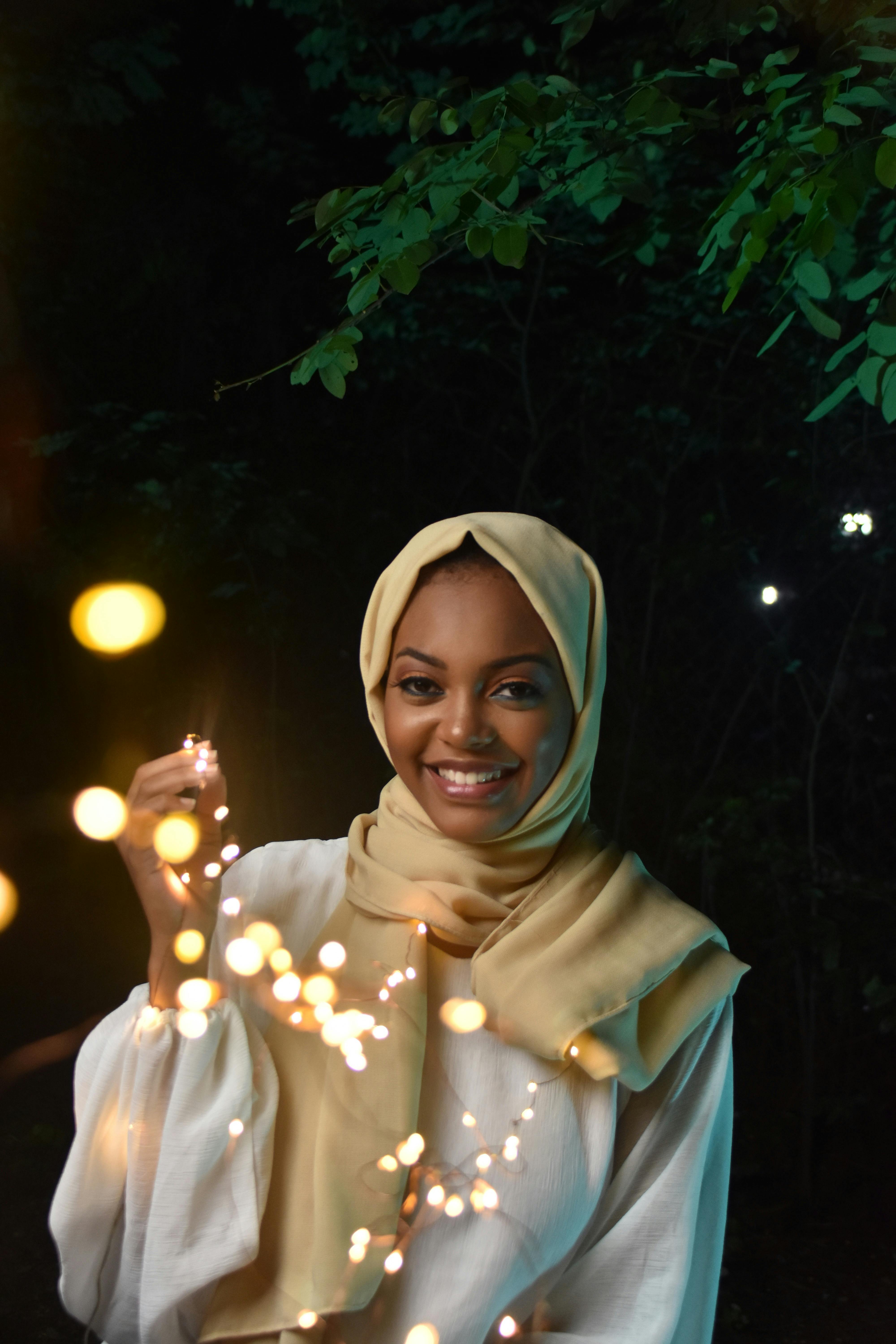 一位快乐的蒙面女子在树灯下享受着闪闪发光的庆祝活动