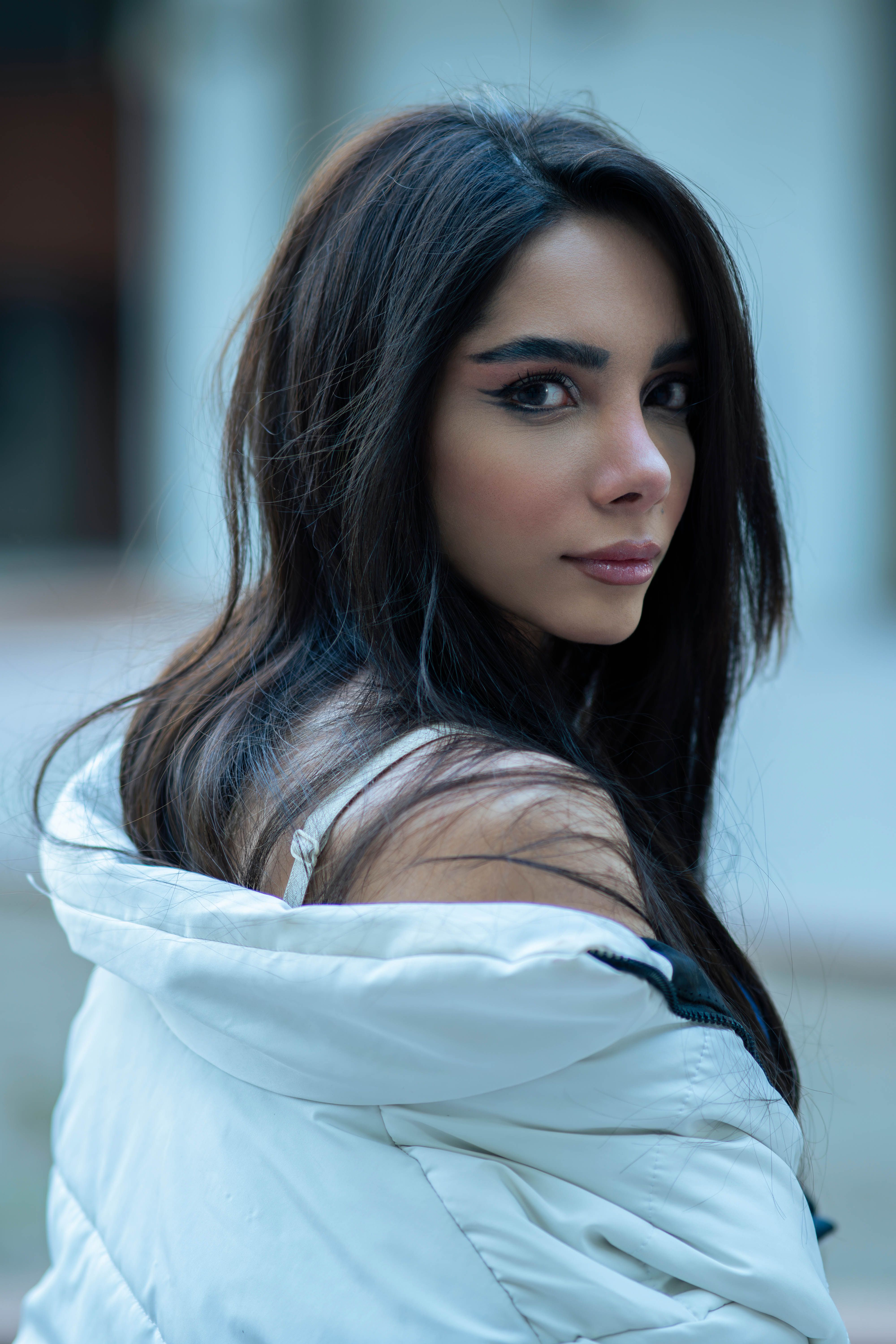 Elegant woman in white jacket captured outdoors in Tehran, showcasing modern fashion.