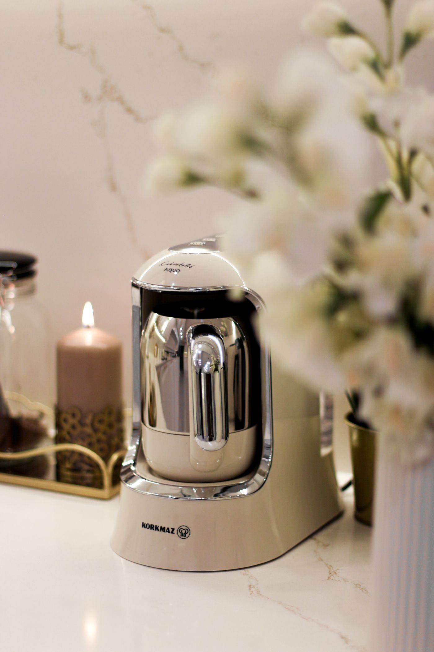 Elegant kitchen countertop featuring a modern coffee maker, flowers, and warm decorative details