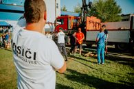 A group of firefighters in a park setting during a public demonstration near a fire truck.