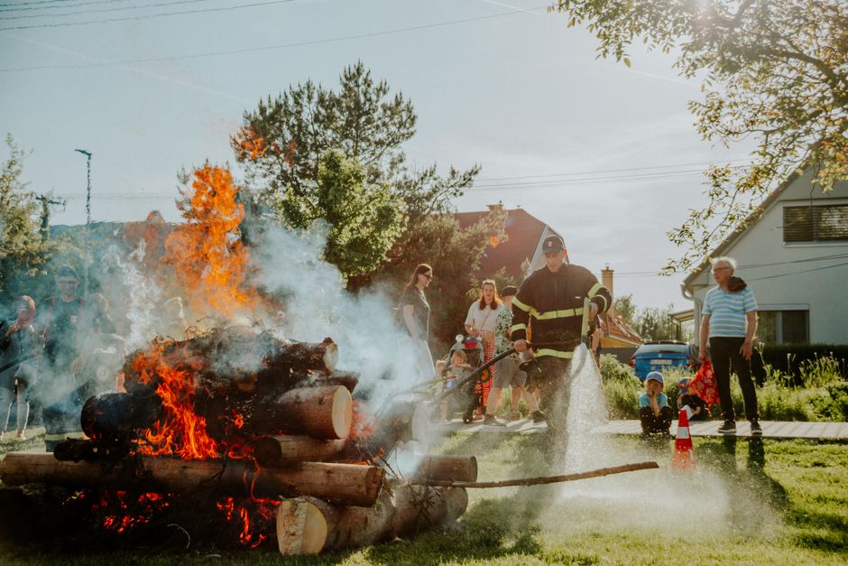 Firefighter putting out a controlled fire during a training demonstration in a residential area.