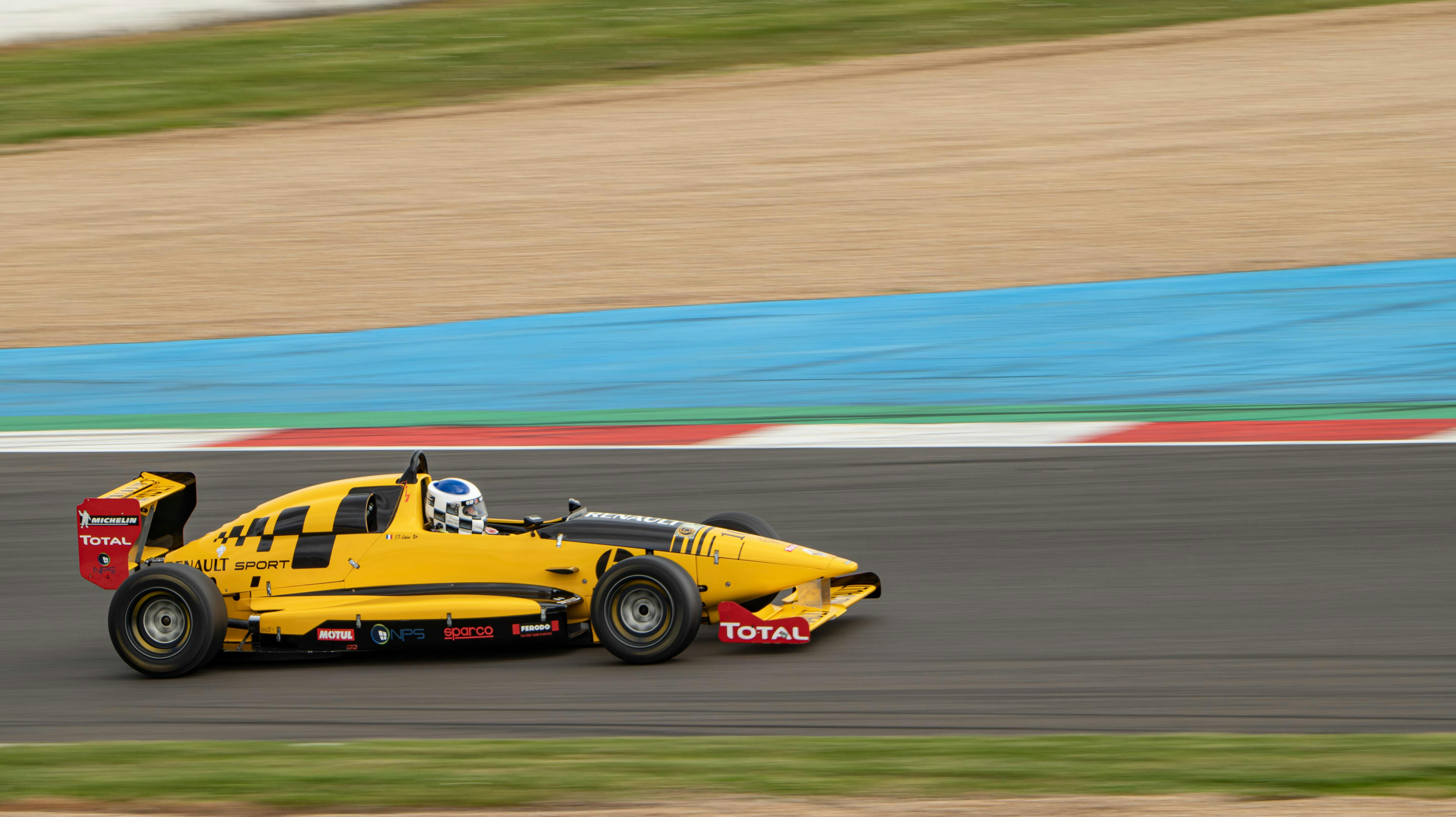 Dynamic image of a yellow Renault racing car in action on a professional race track.