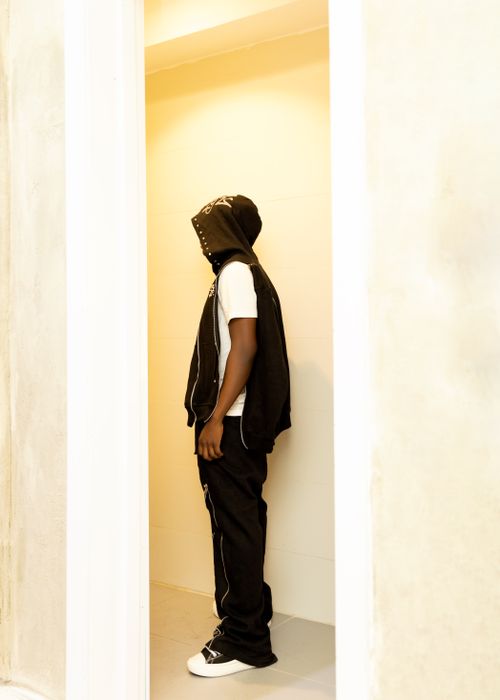 Free Man in a stylish black hoodie stands in a minimalistic indoor setting. Stock Photo