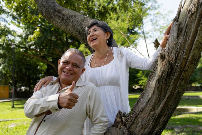 Pareja hispana de adultos mayores disfrutando al aire libre — MedicareAliado les ayuda a encontrar el mejor plan