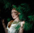 一位年轻女子在自然光下，与郁郁葱葱的绿叶合影