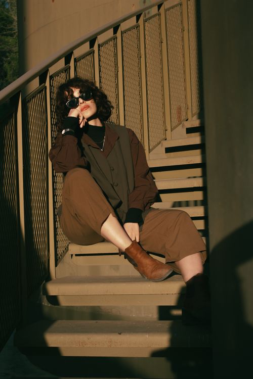 Free Fashionable woman in sunglasses sitting on stairs during golden hour. Stock Photo