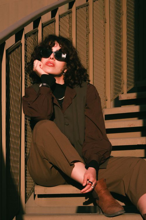 Free Fashionable woman in sunglasses seated on staircase, urban style. Stock Photo
