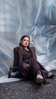 A fashionable woman poses elegantly outdoors against a modern backdrop.