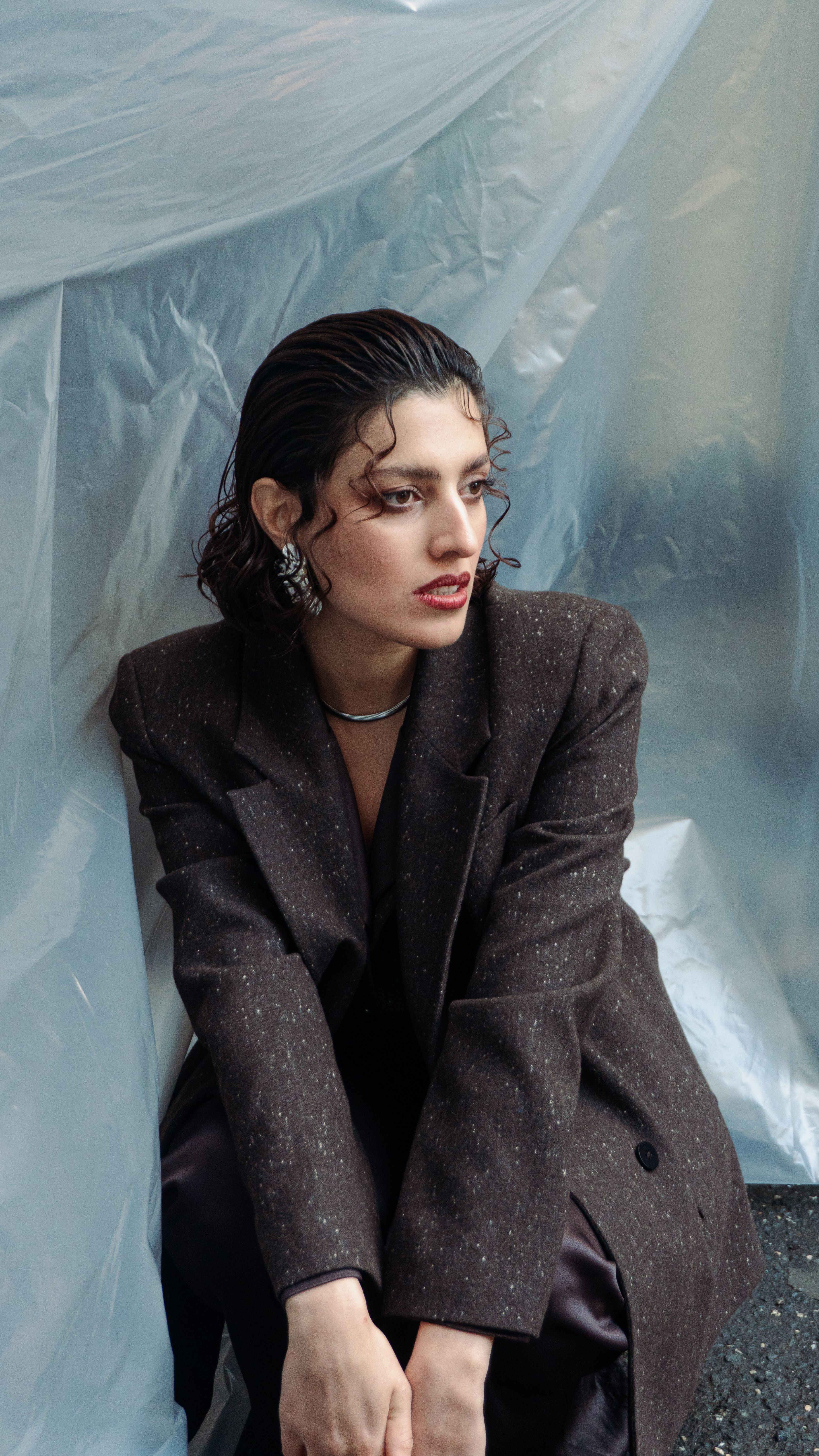 A fashionable woman with wet hair poses in an urban setting, showcasing trendy style.