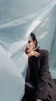 A striking portrait of a woman with plastic draped over her, emphasizing fashion and emotion.