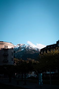 Stunning view of snow-capped mountains in Switzerland behind urban architecture and trees.