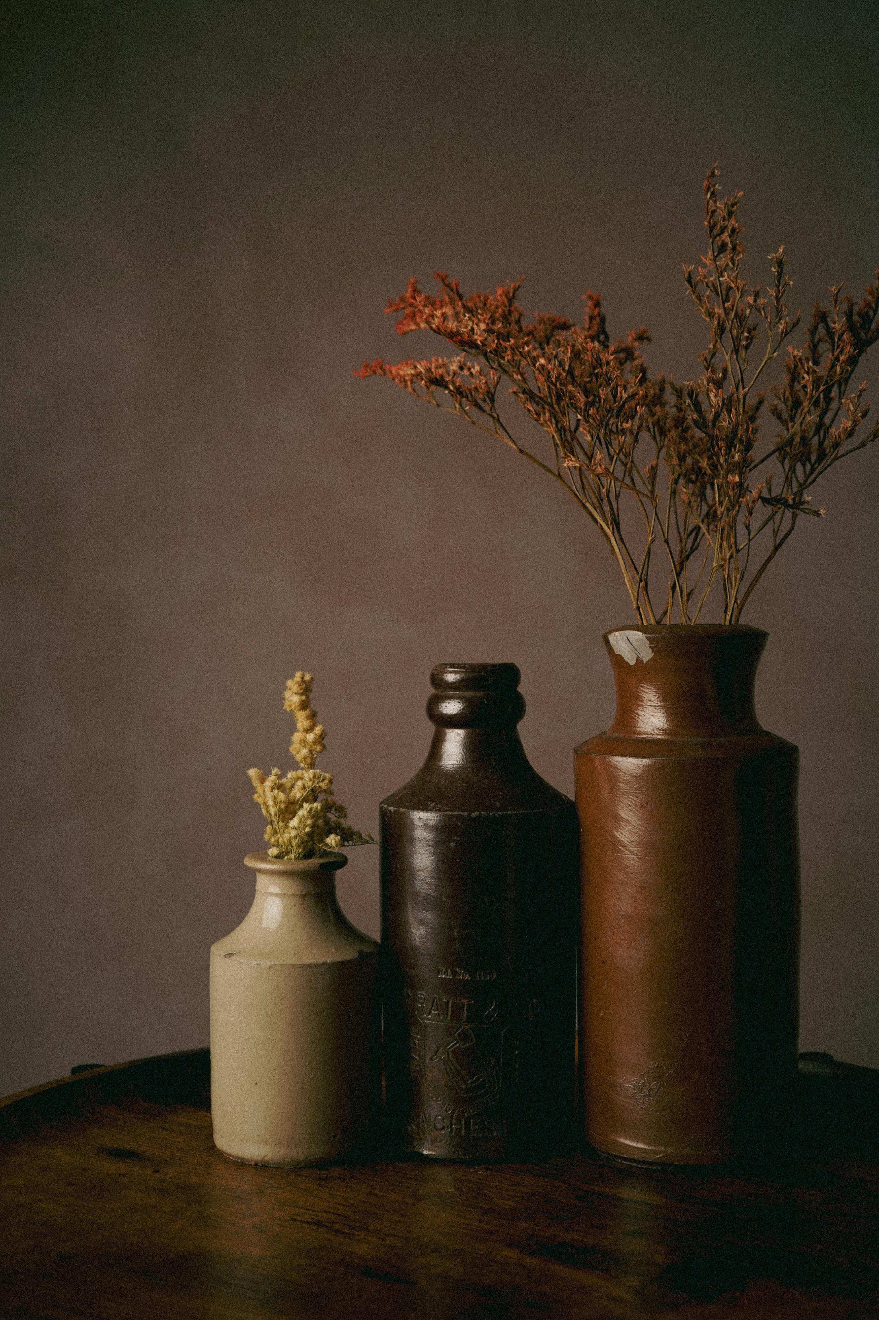 Aesthetic display of vintage ceramic vases with dried flowers on a wooden table.