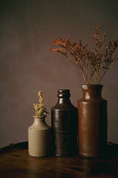 Aesthetic display of vintage ceramic vases with dried flowers on a wooden table.
