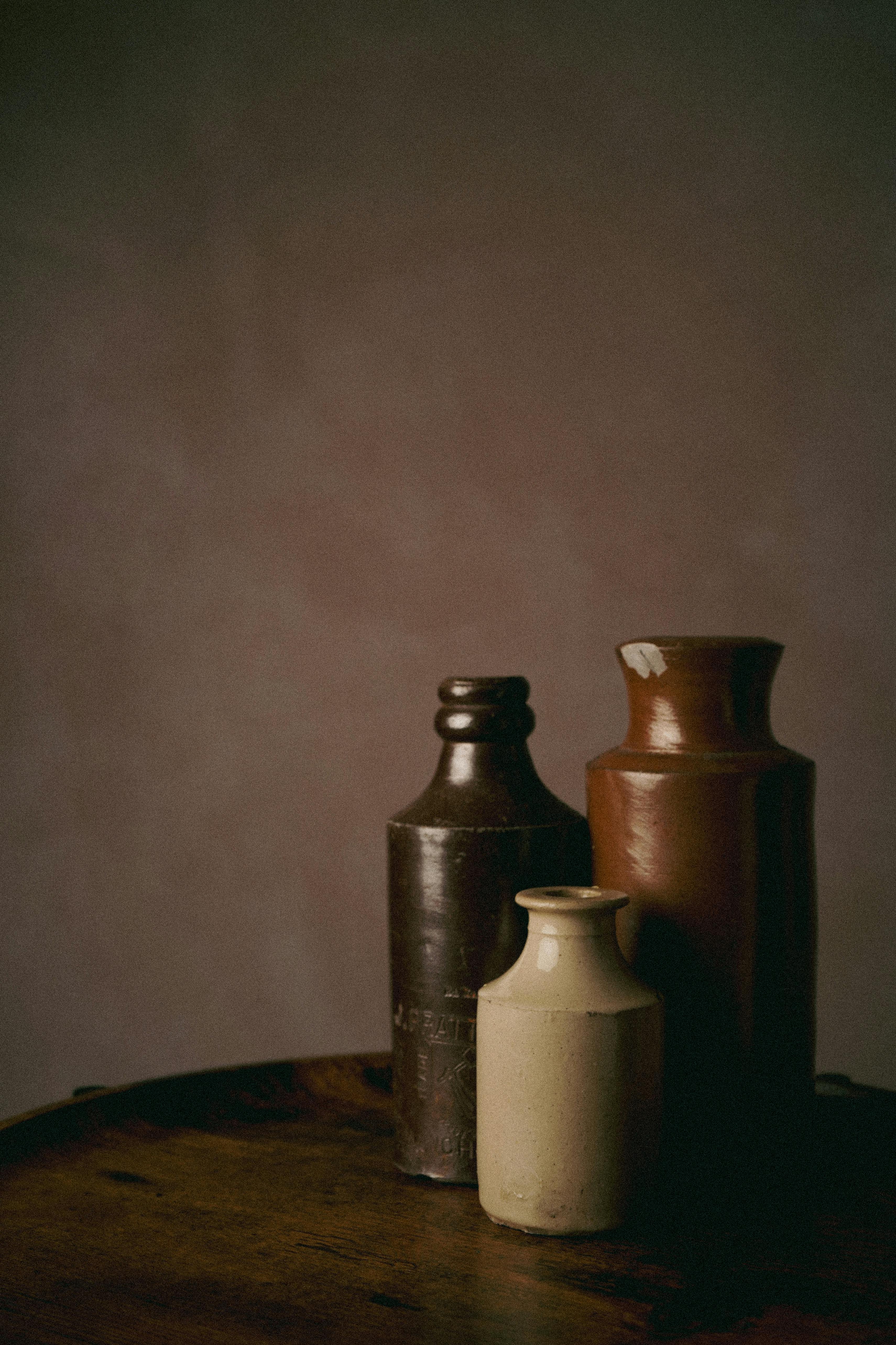 Three rustic ceramic pots on a wooden surface, captured in warm lighting, showcasing vintage charm.