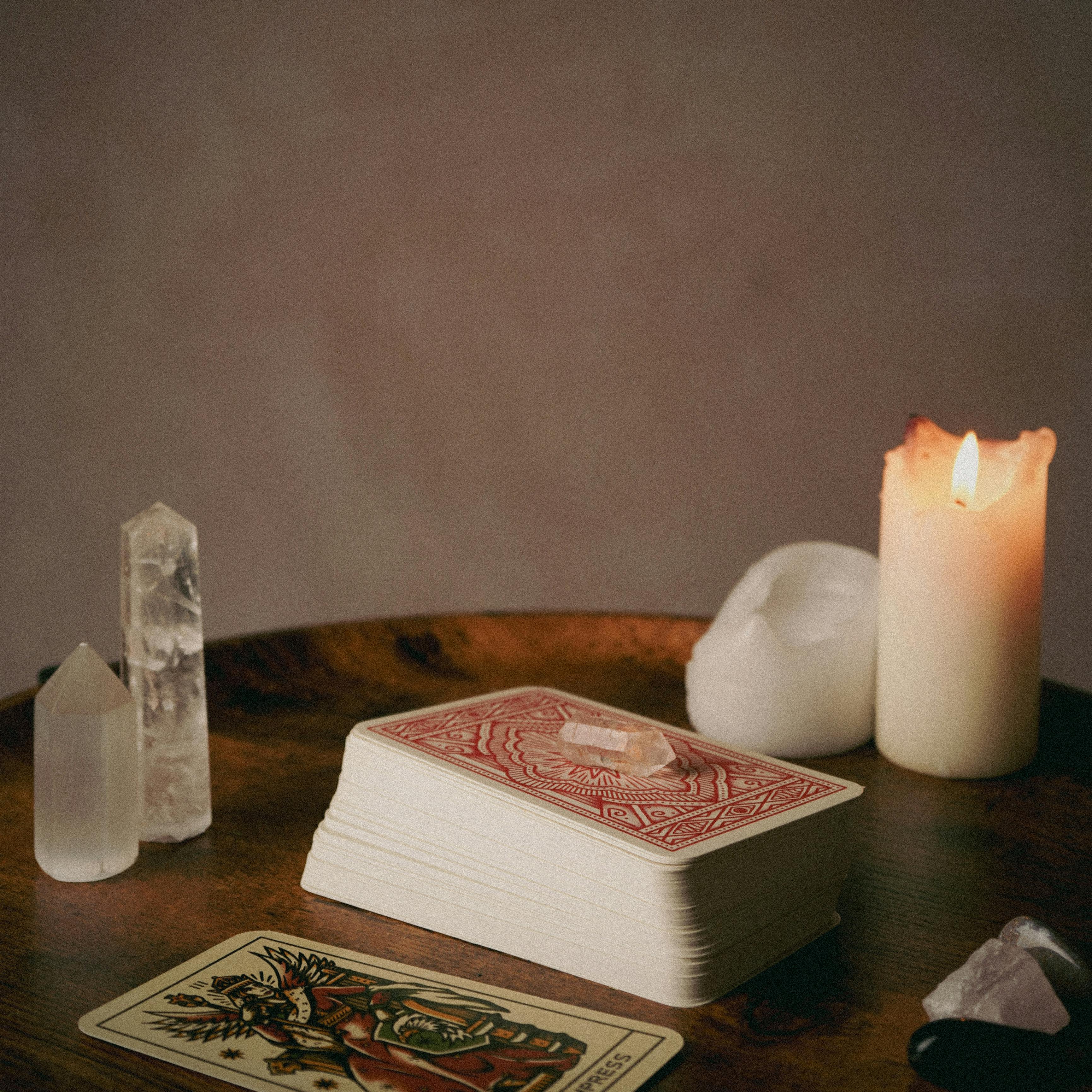 A mystical setup featuring tarot cards, crystals, and candles on a wooden table.