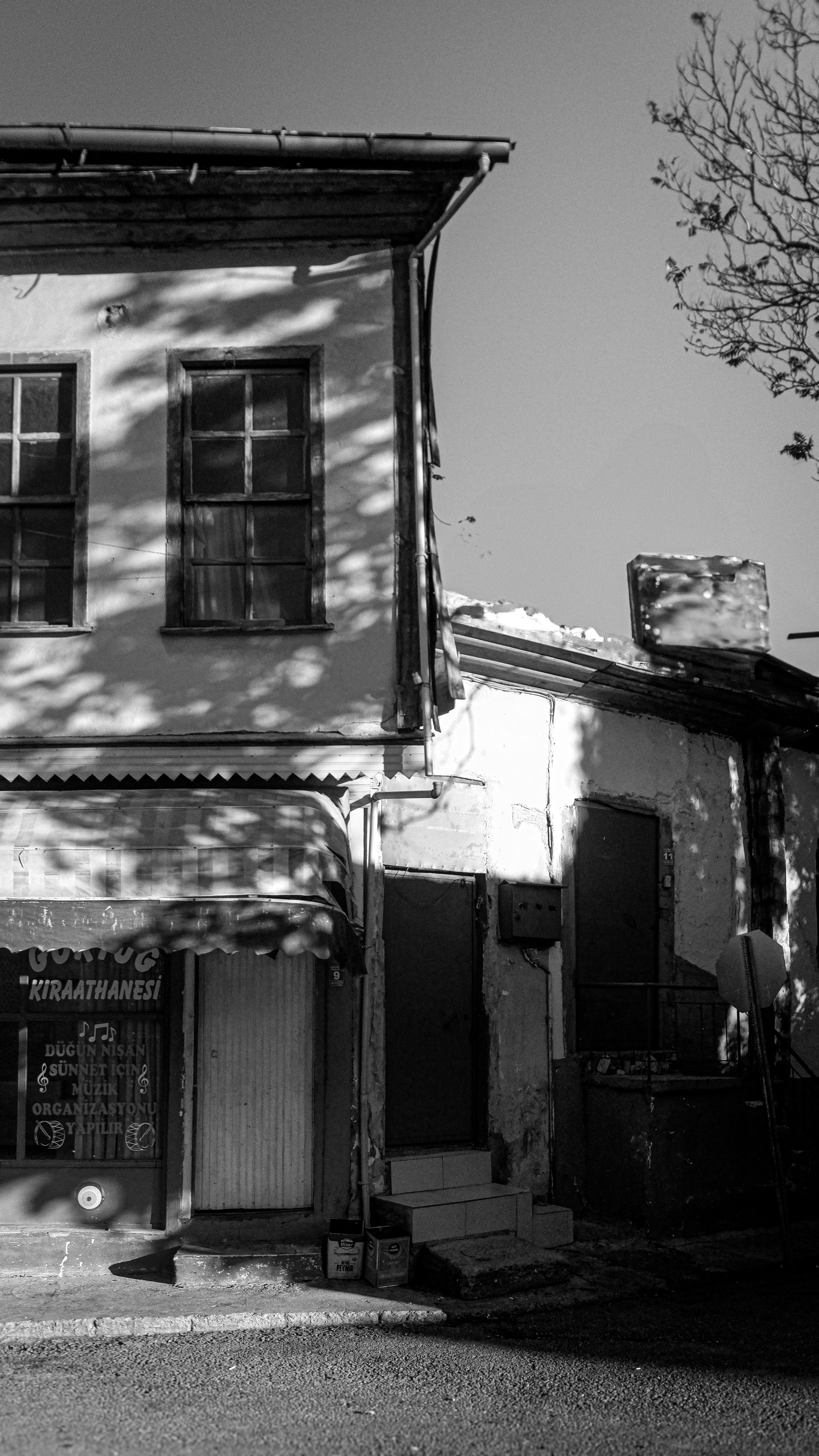 Black and white photo of an old building with vintage architectural elements, casting dramatic shadows.