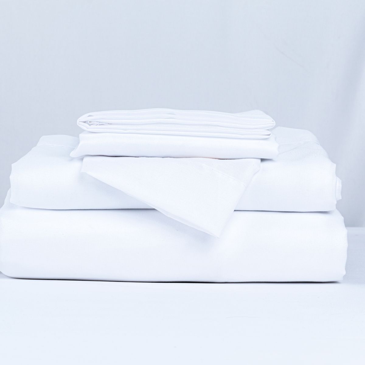 Pilha de roupas de cama brancas dobradas sobre uma superfície