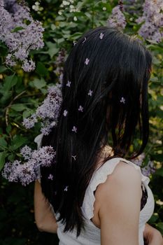 Elegant woman with lilac flowers in hair enjoying nature outdoors.