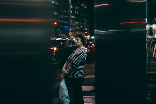 An Elderly Woman Standing while Holding a Plastic Bag