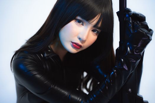 Woman in black leather outfit posing with mysterious gaze, indoors.