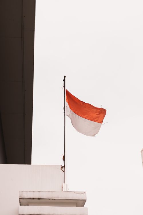 Free The Indonesian flag waves prominently against a clear sky, symbolizing national pride. Stock Photo