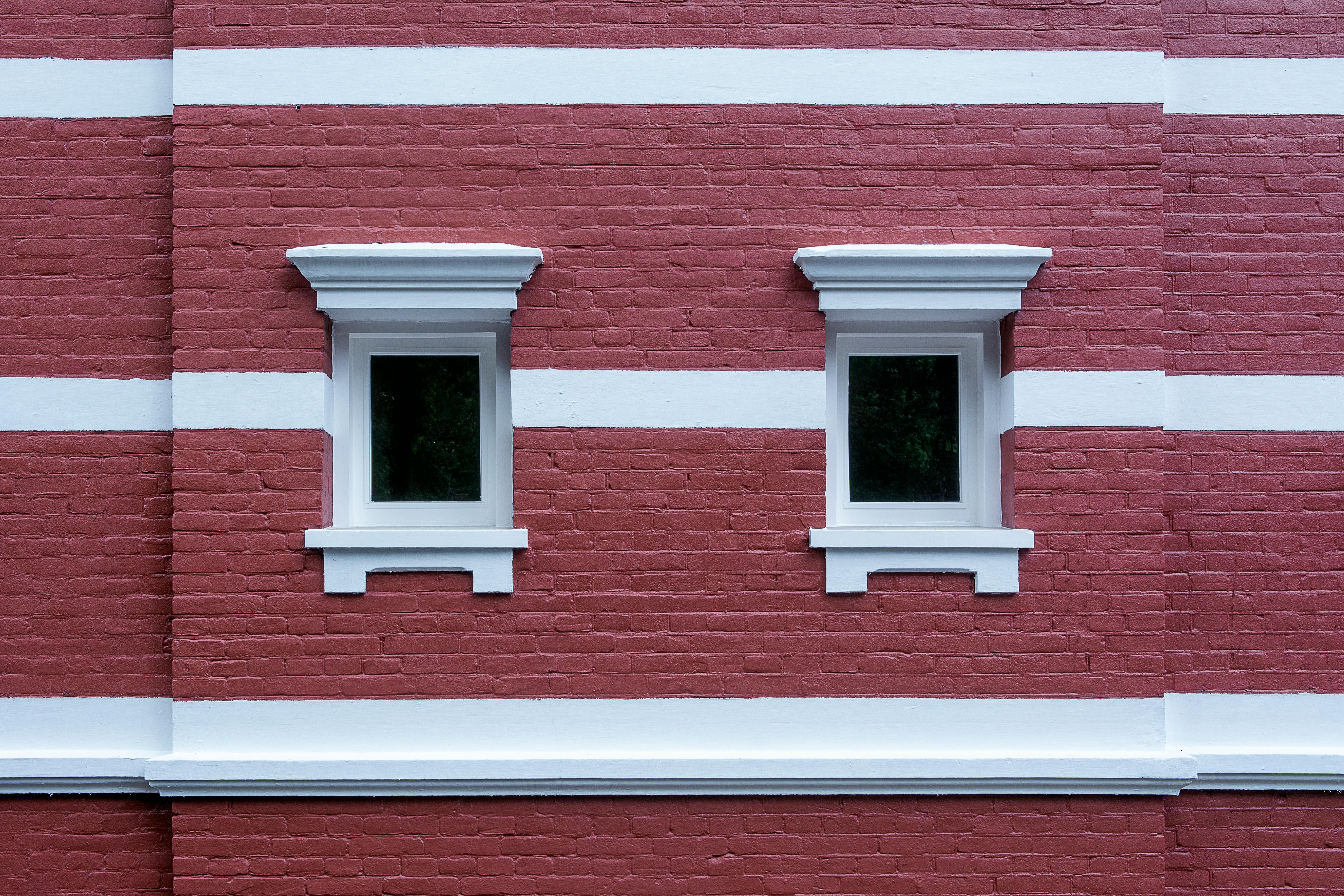 Gratis Vista simétrica de dos ventanas en una fachada de ladrillo rojo con rayas blancas. Foto de stock