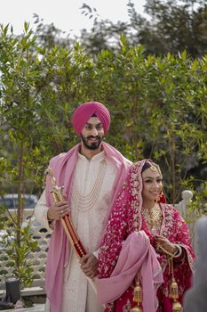 Traditional Indian wedding couple posing outdoors in Delhi, India.