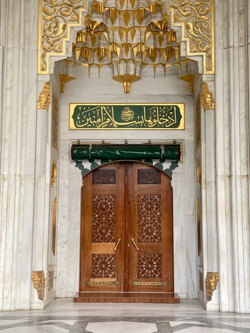 Free Elegant mosque doorway with detailed carvings and Arabic calligraphy. Stock Photo