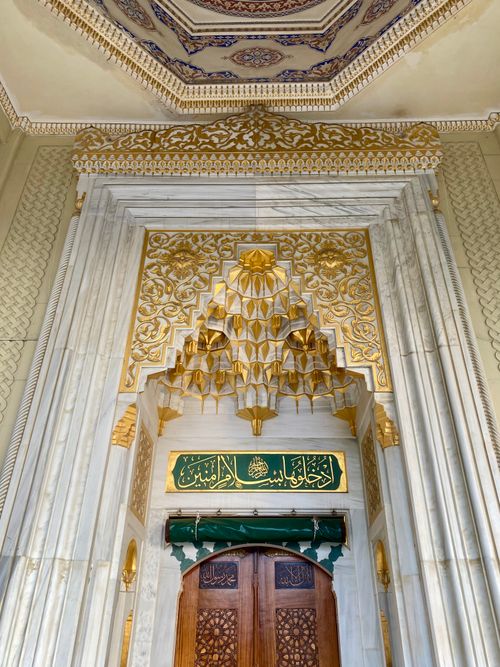 Free Marble archway adorned with golden Islamic patterns and Arabic calligraphy. Stock Photo