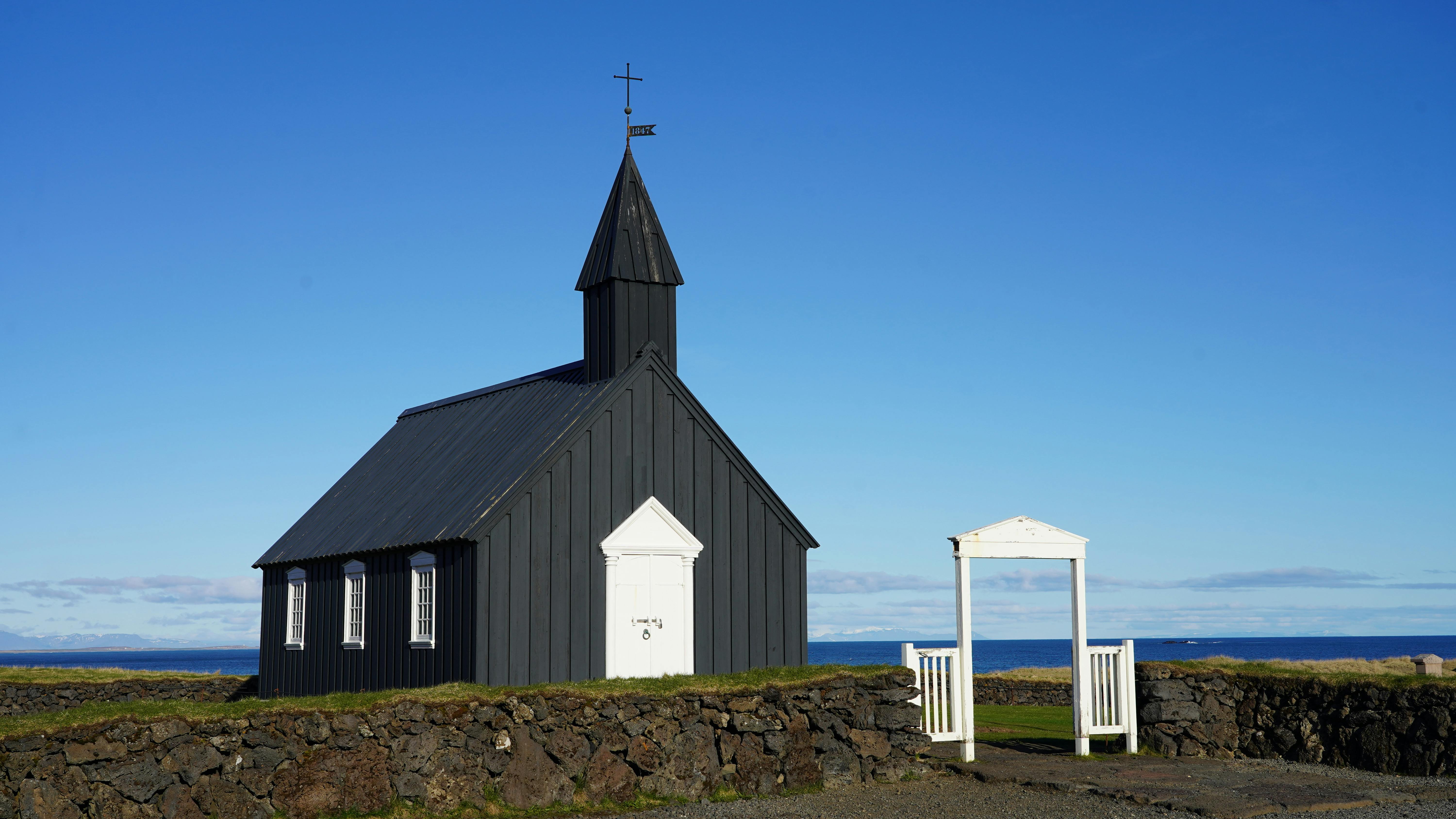A Church with a Black Exterior Wall on the Green Grass · Free