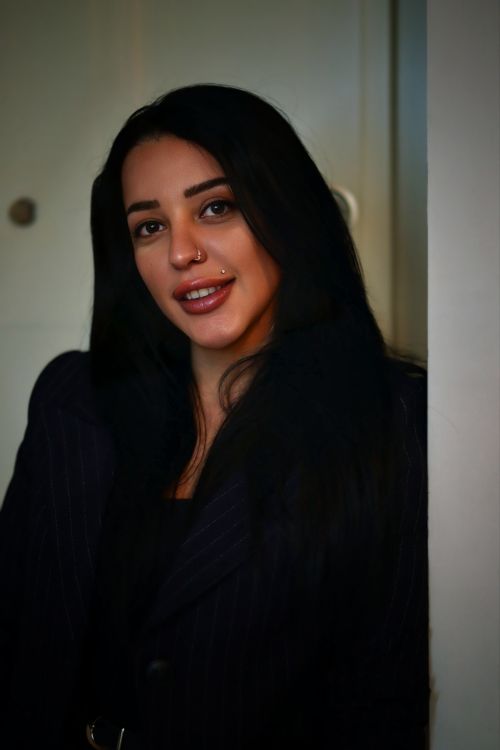 Free Stylish woman indoors with long dark hair and a nose ring, smiling confidently. Stock Photo
