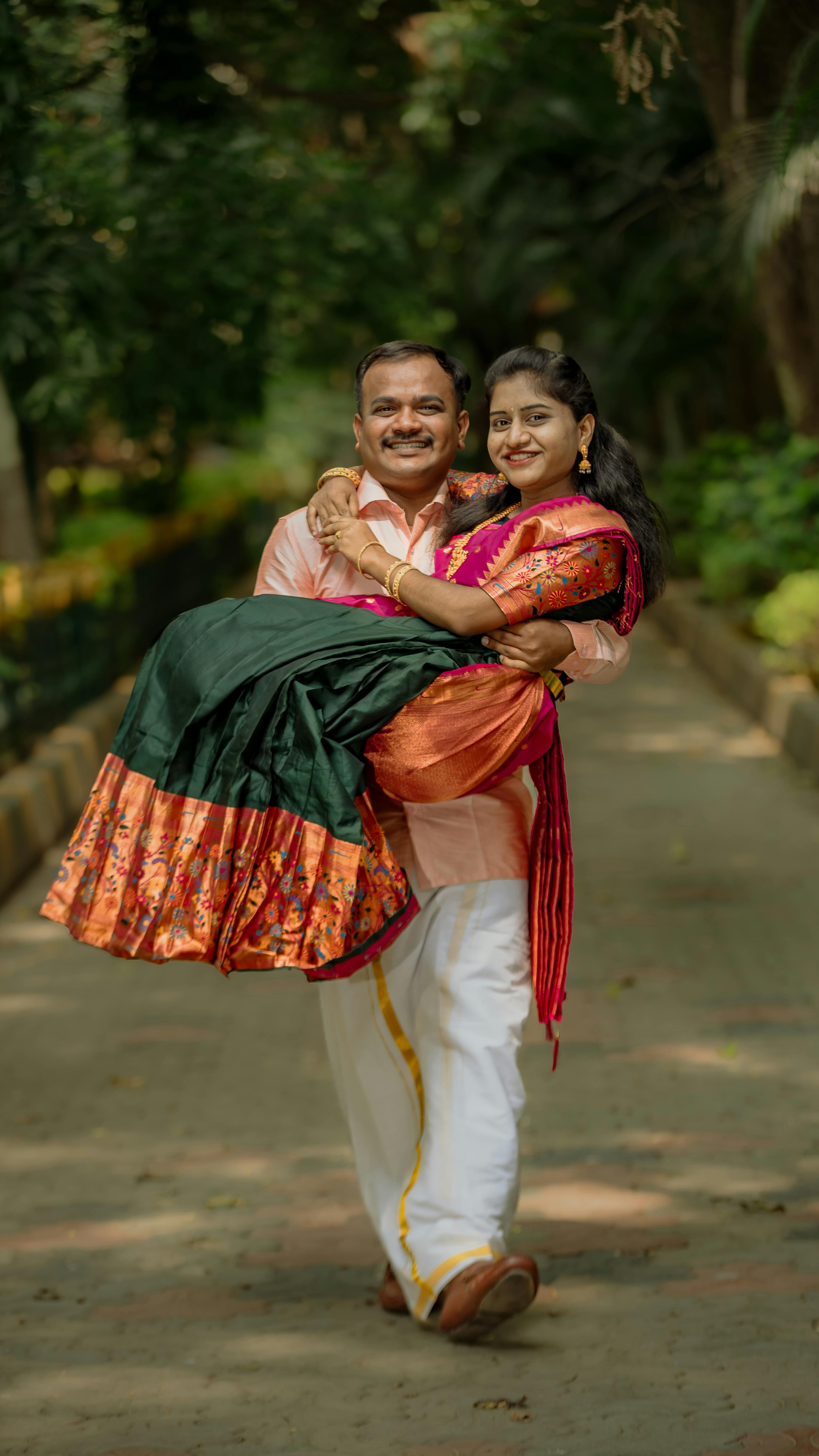 Joyful couple in vibrant traditional Indian clothing enjoying a sunny day outdoors.