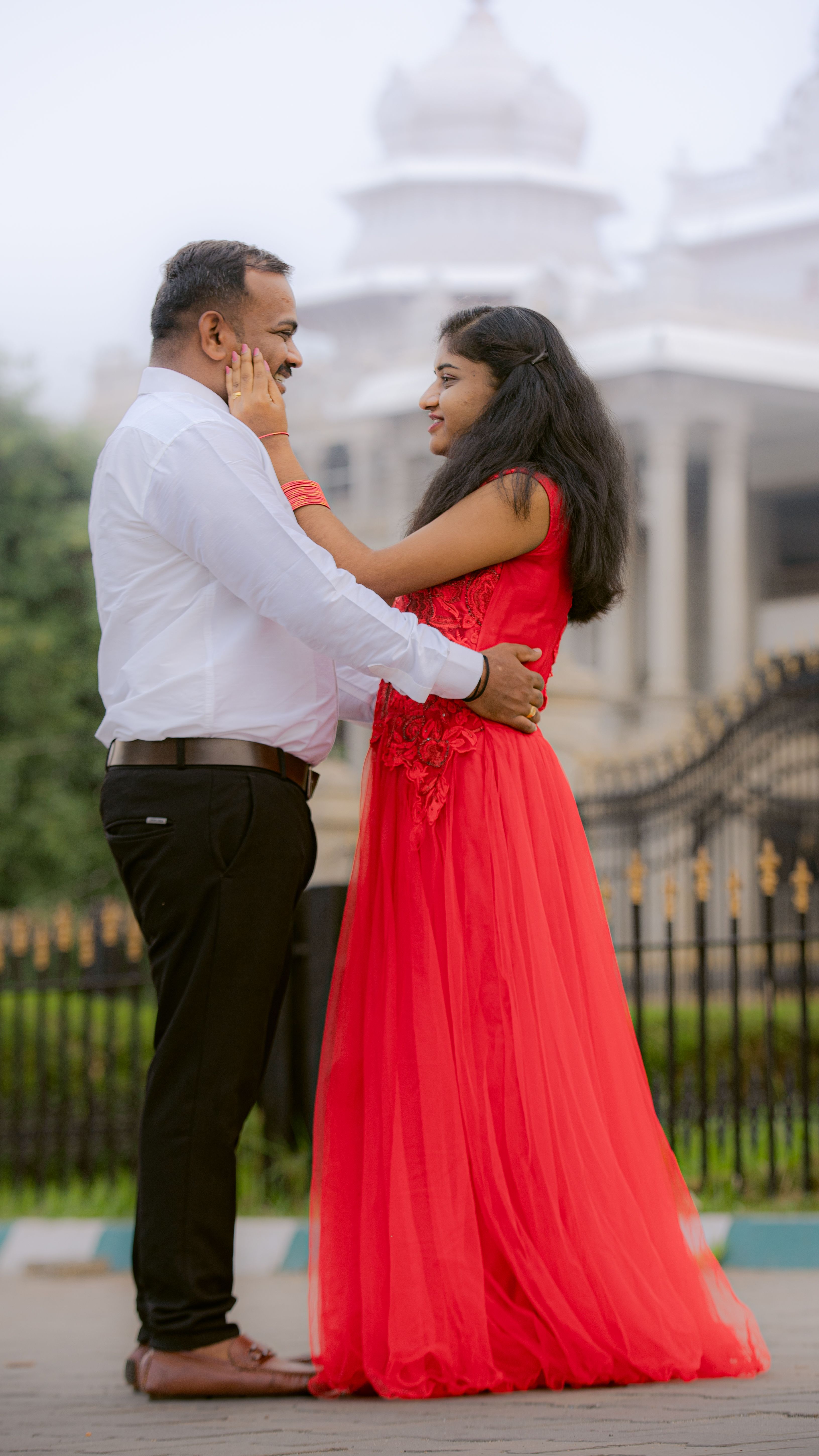 A couple embraces lovingly near a grand historic building with ornate architecture.