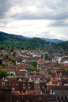A picturesque aerial view of a European village with lush green hills in the background.