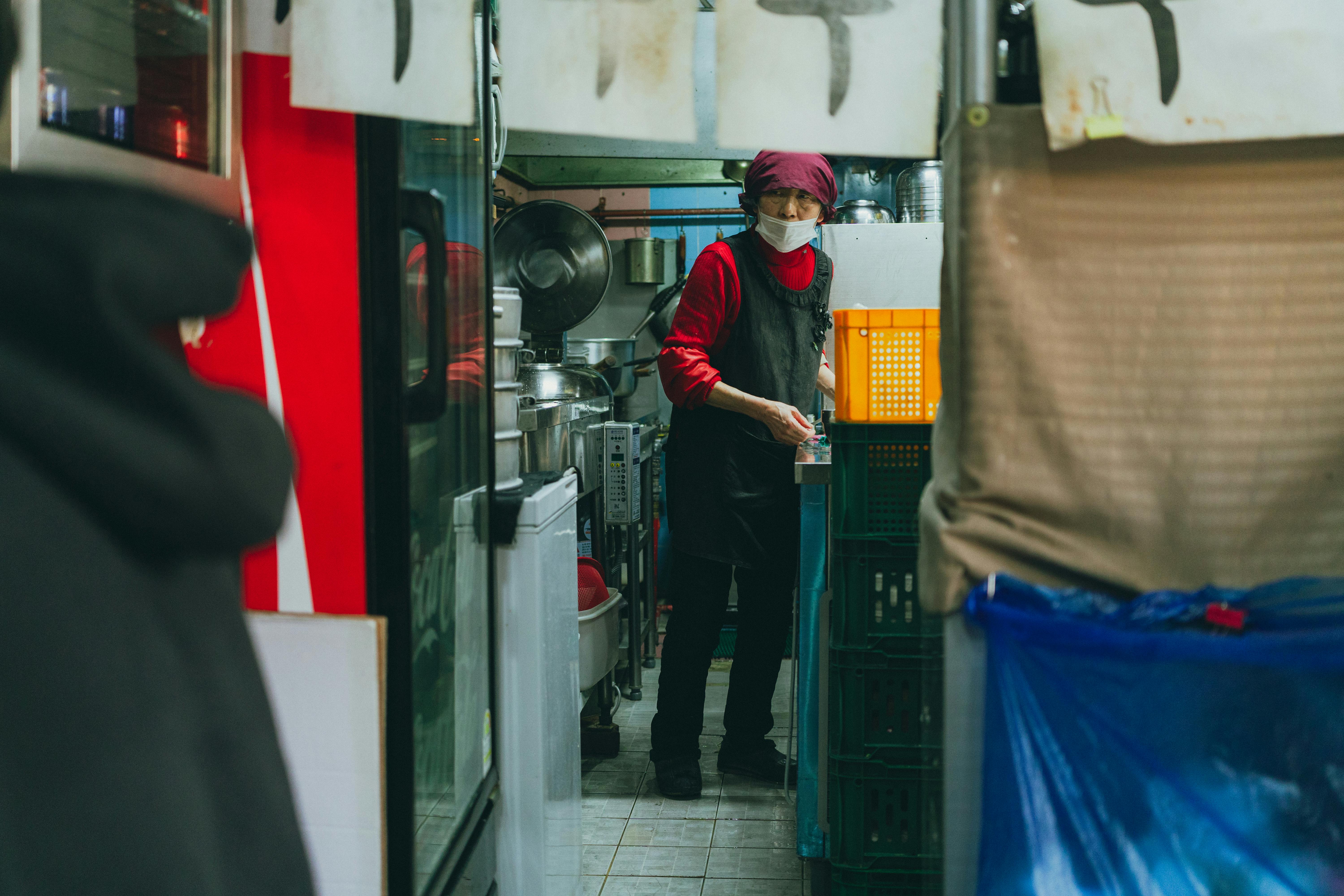 A street vendor prepares food in a bustling Seoul market kitchen.