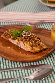 Delicious salmon fillet garnished with herbs and a lemon slice on a wooden plate.