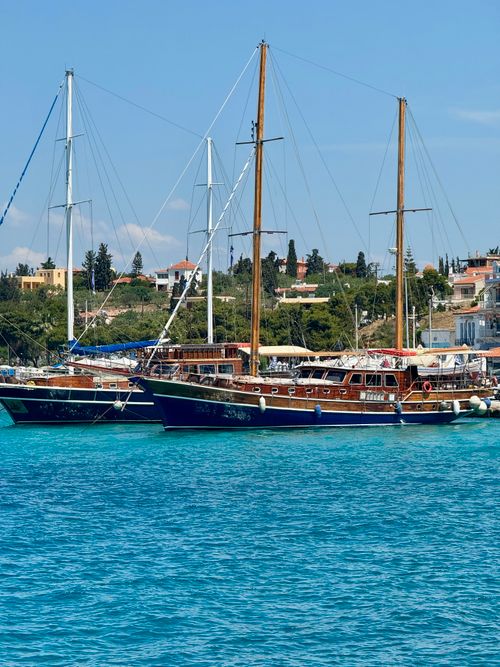 Free Two classic wooden boats anchored in clear turquoise waters near a coastal town. Stock Photo