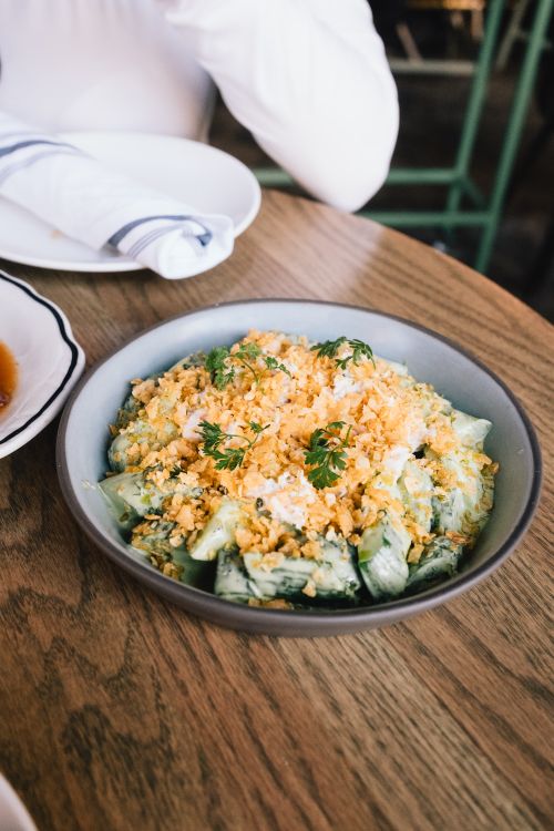 Free Delicious cucumber salad topped with crispy crumbs in a bowl on a wooden table. Stock Photo