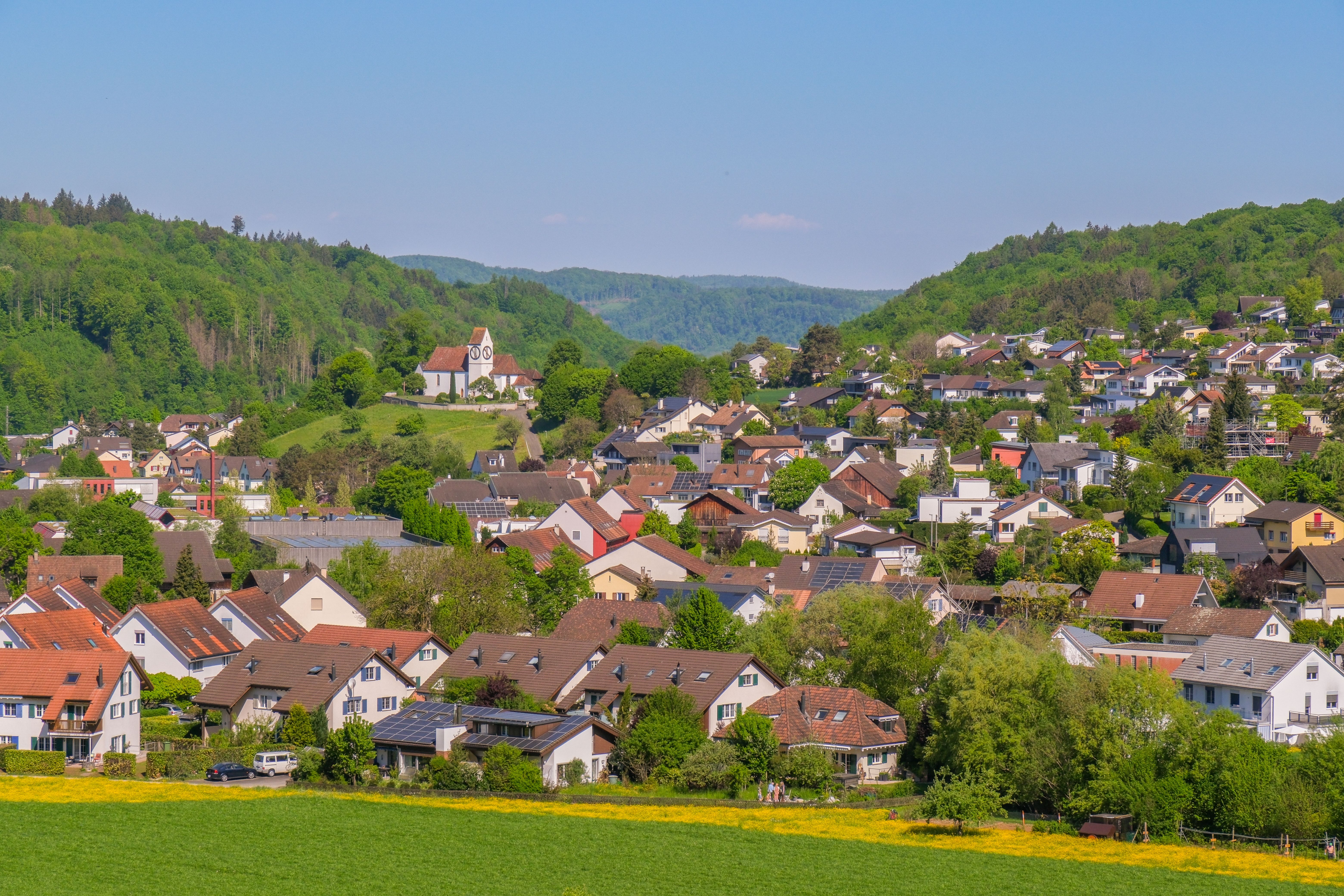 A village among green hills under an open sky in the European countryside