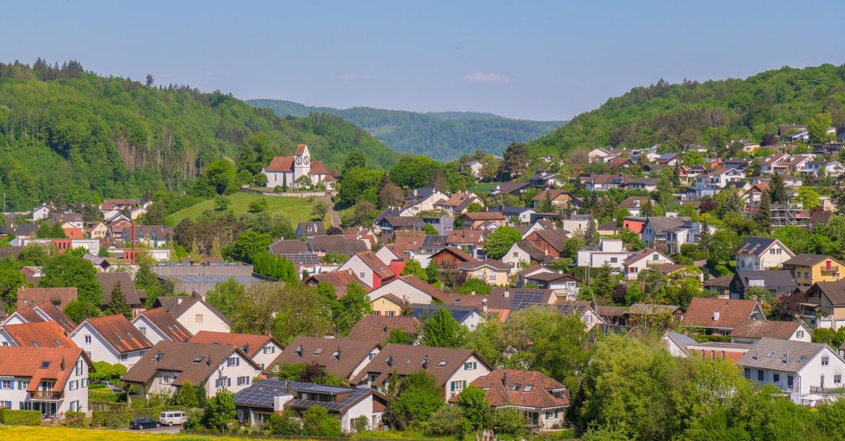 A village among green hills under an open sky in the European countryside