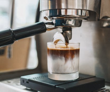 Espresso machine pouring coffee into milk in Tokyo's Shinjuku café, creating a visually appealing layered drink.