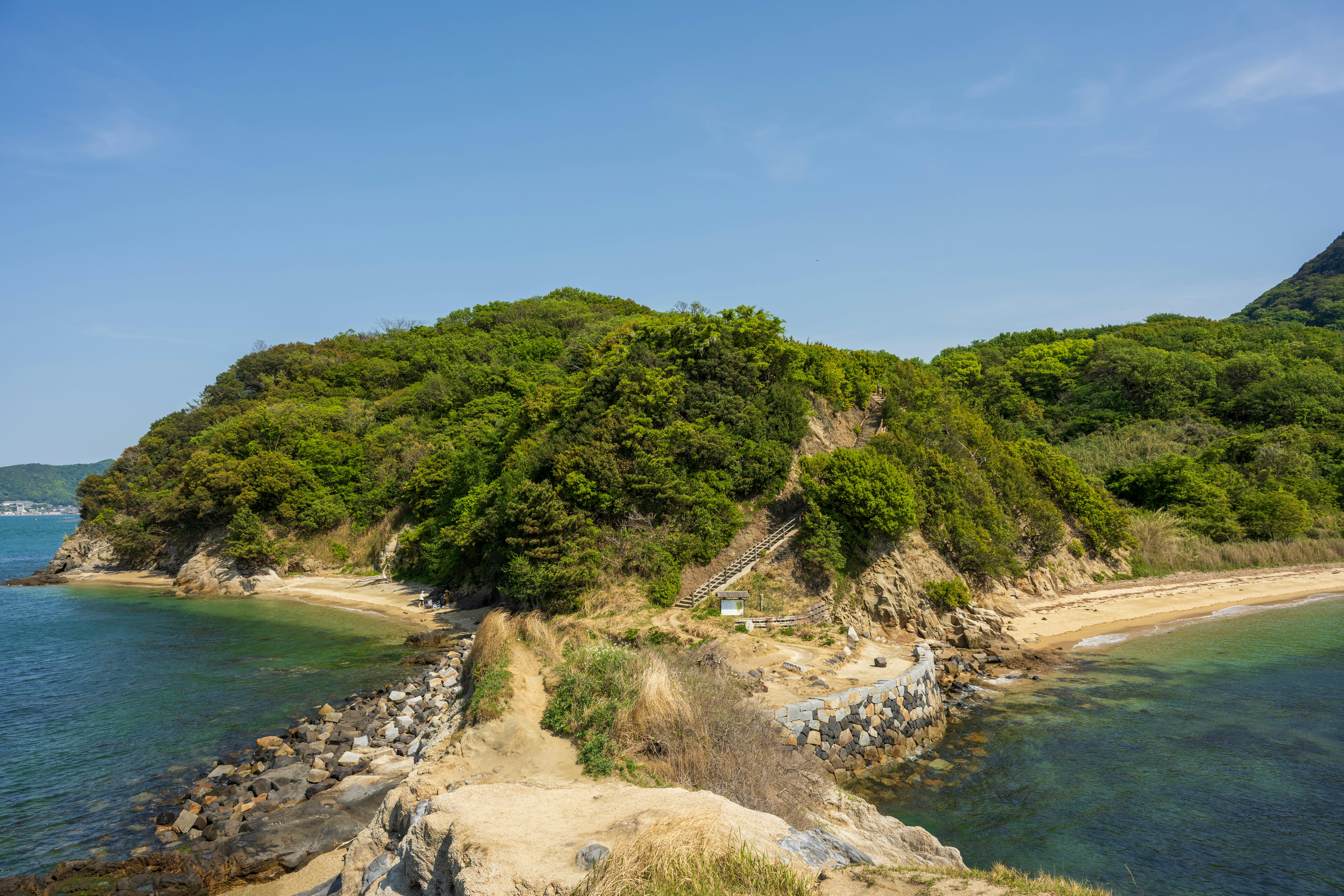 A picturesque coastal scene featuring lush green cliffs and rocky beaches under a bright blue sky.