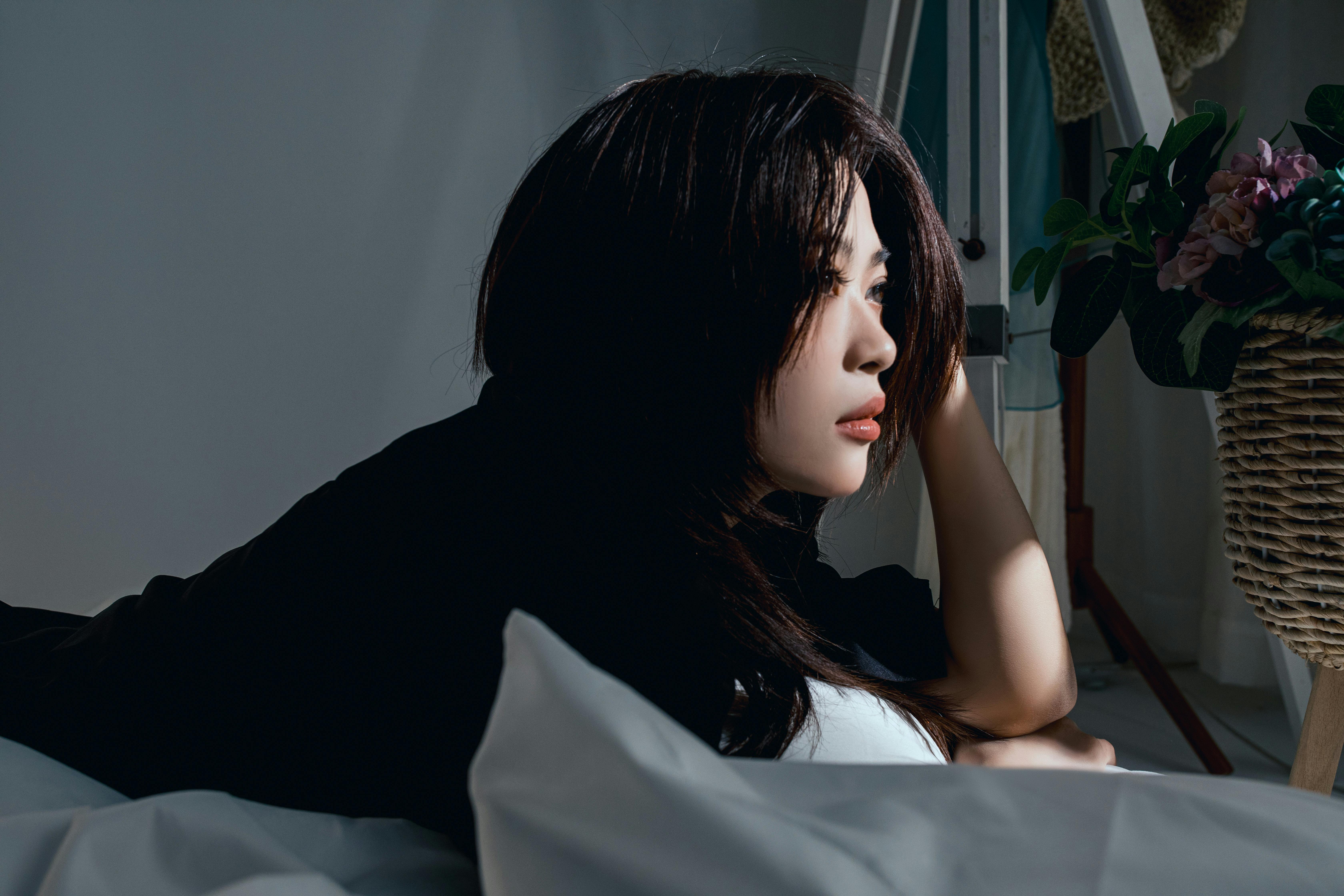 A serene scene of a woman relaxing indoors, enveloped in soft light and shadows.