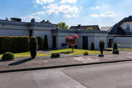 Contemporary suburban house with meticulous landscaping and modern architectural design on a sunny day.