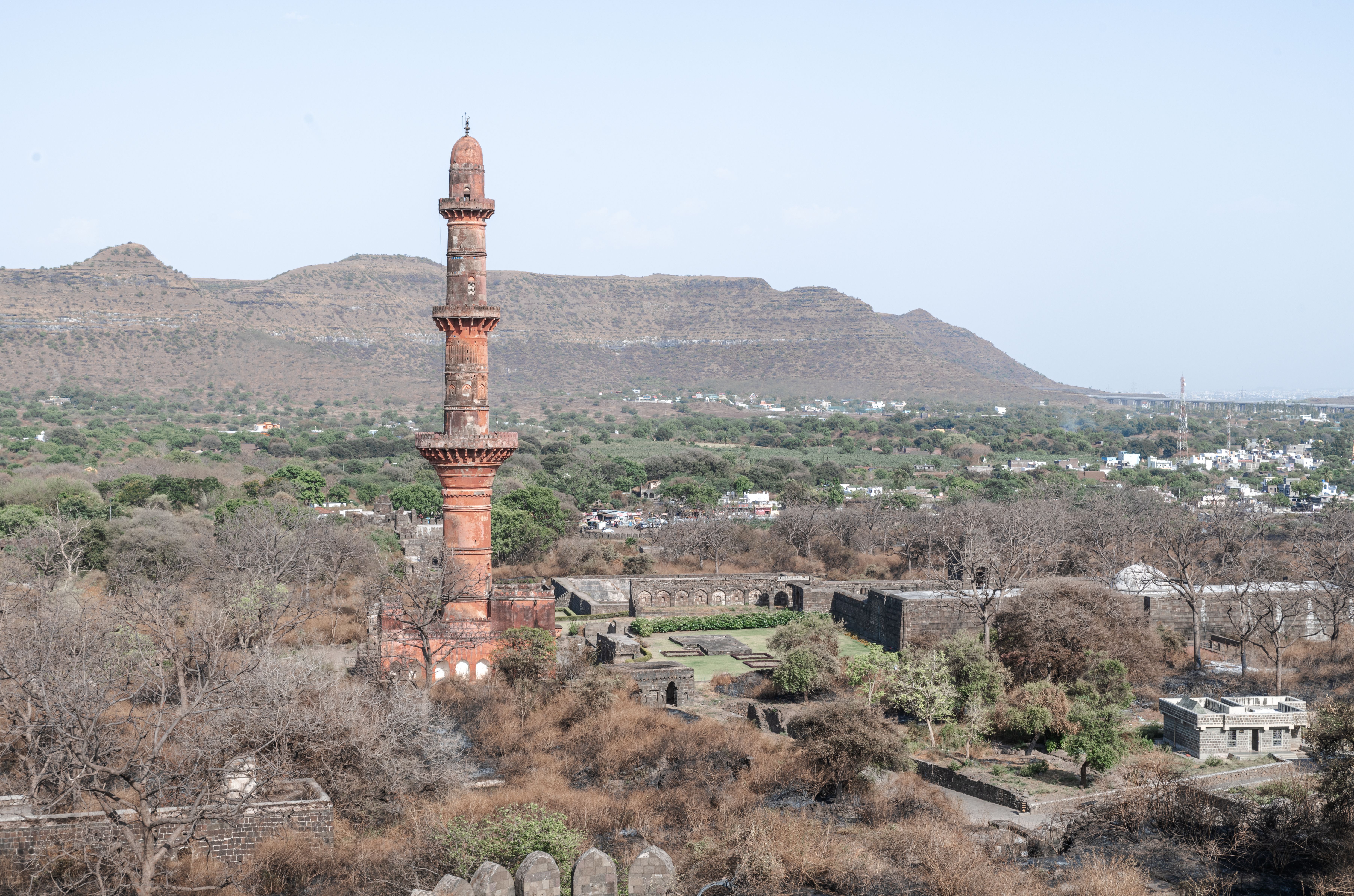 Explore the historic Chand Minar in Daulatabad, India, surrounded by lush hills and ancient architecture. - Chand Baori