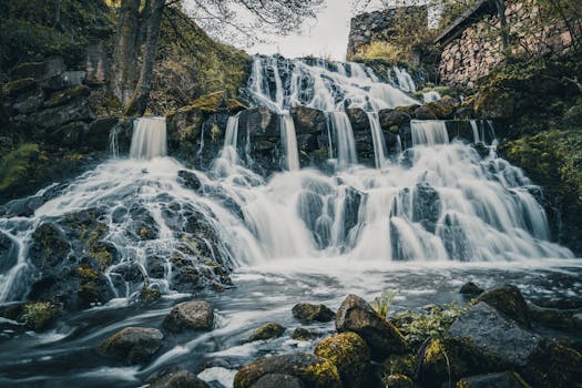 Beautiful cascading waterfall surrounded by lush greenery in a tranquil outdoor setting.
