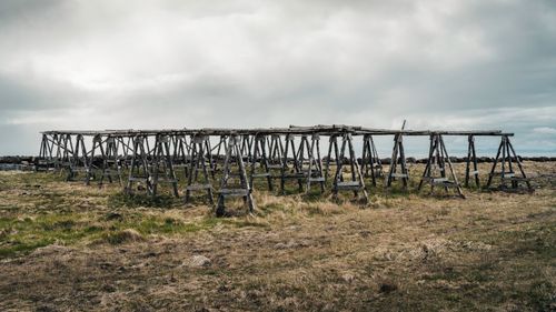 Free Wooden fish drying racks in a rugged Icelandic landscape under cloudy skies. Stock Photo
