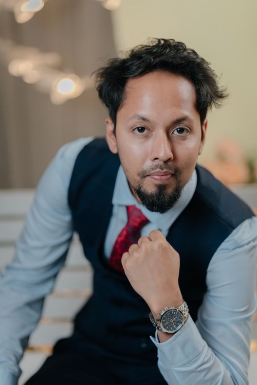 Free Portrait of a confident businessman wearing a stylish suit and watch, posing indoors with a thoughtful expression. Stock Photo
