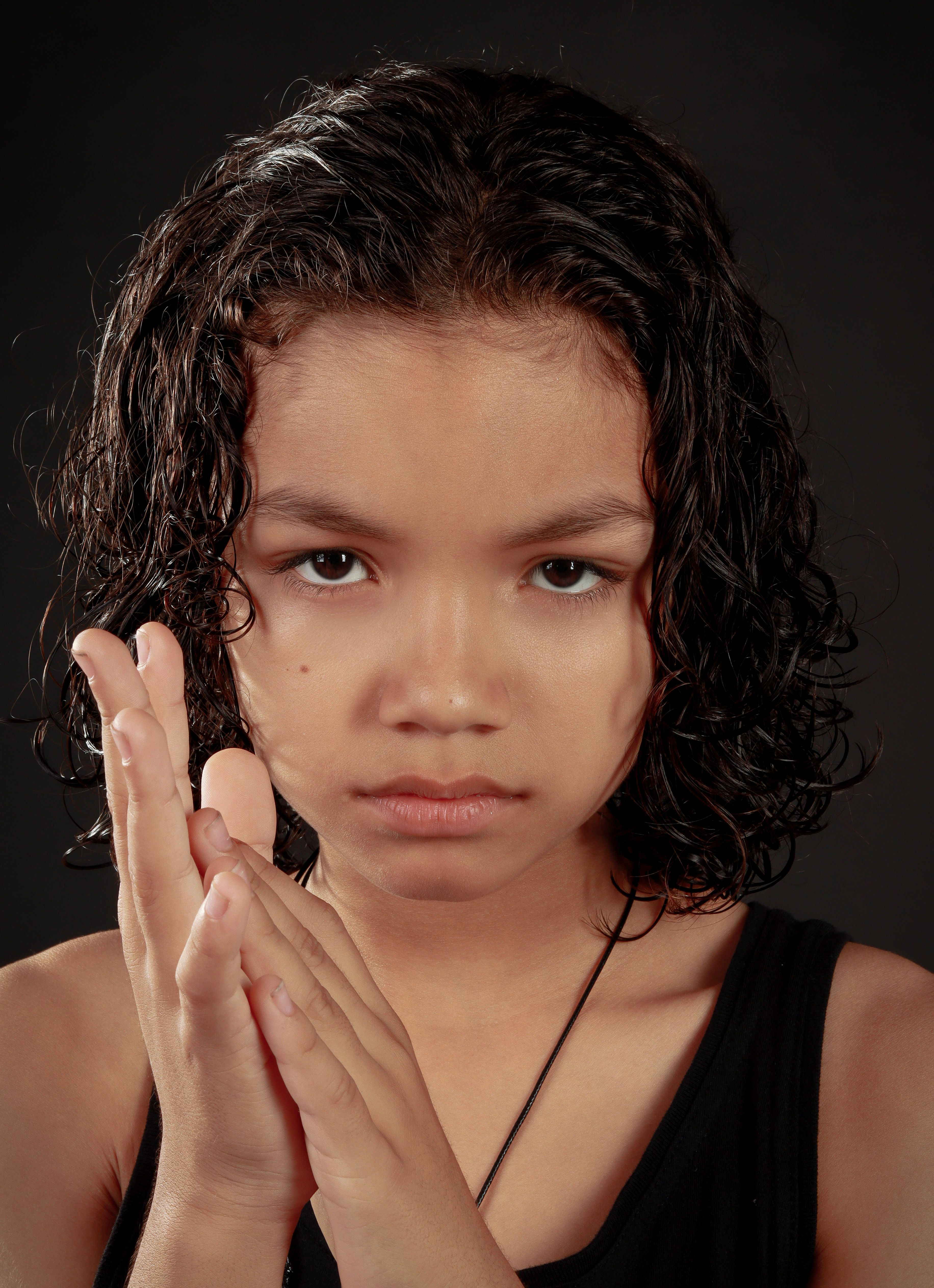 Close-up portrait of a young girl with wet hair, showing a determined expression against a dark background.